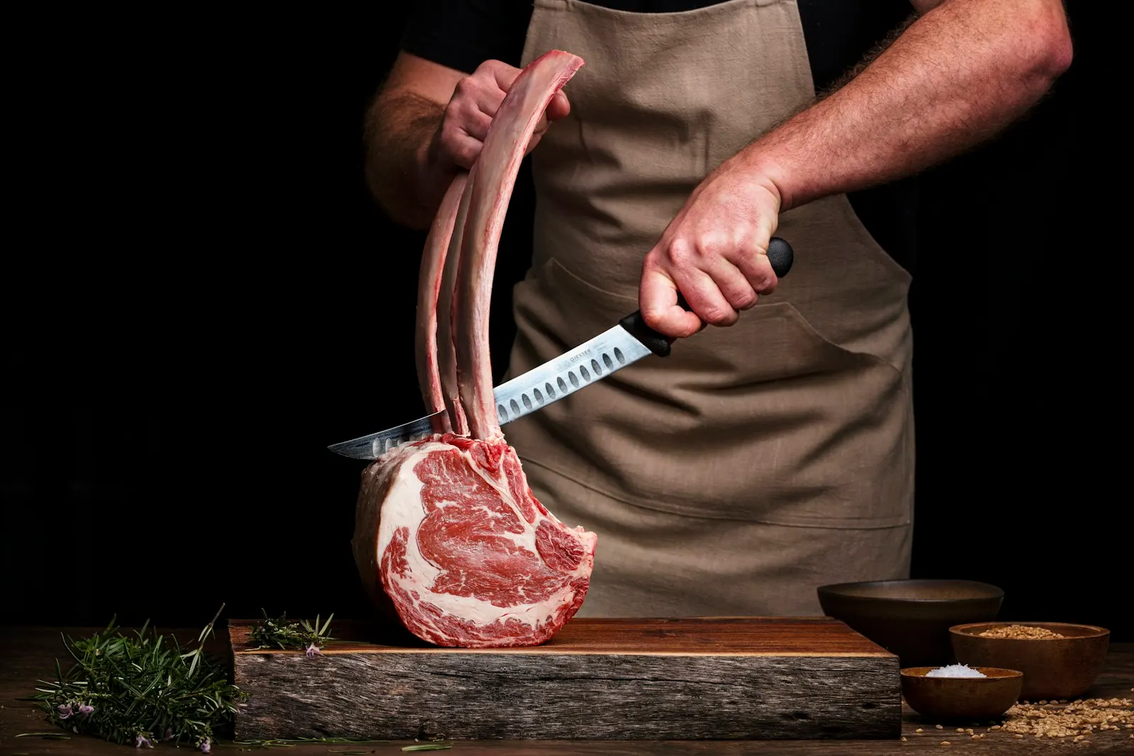 Le boucher pare une côte de bœuf au couteau, à l’atelier