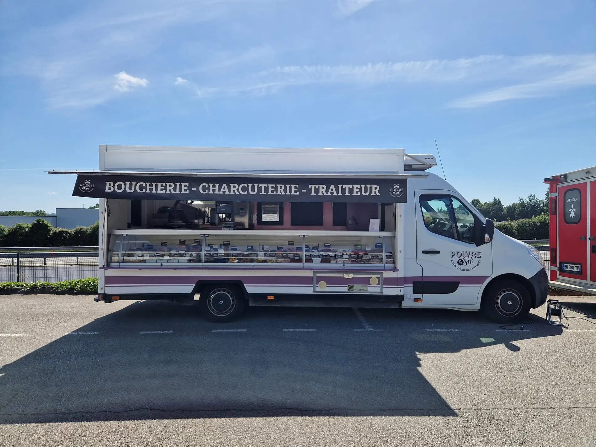 Le camion Poivre et sel ouvert sur un marché : étal réfrigéré et enseigne « Boucherie · Charcuterie · Traiteur »